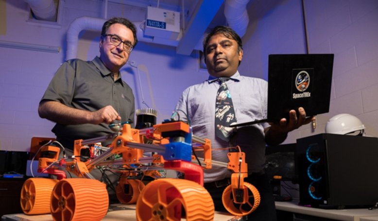 University of Arizona engineering faculty members Jekan Thanga (right) and Moe Momaye are pictured with a 3D-printed rover prototype used for testing a new generation of miniature sensors for applications in lunar mining. Image: Chris Richards/UoA