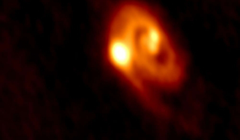 Image captured by ALMA of the tri-system L1448 IRS3B and the disk material around the stars and the spiral arms. The system spans a region about five times the size of our own solar system. Image: University of Oklahoma and ALMA