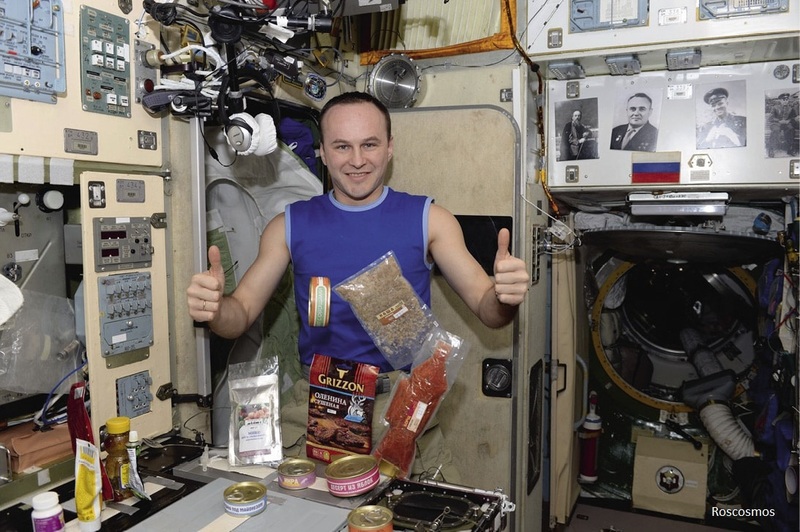 Cosmonaut Sergei Ryazansky showing a set of Russian foods on the ISS.