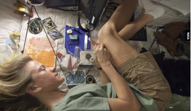 Karen Nyberg hand-stitches her star-themed quilting block during a break from work activities onboard the International Space Station.